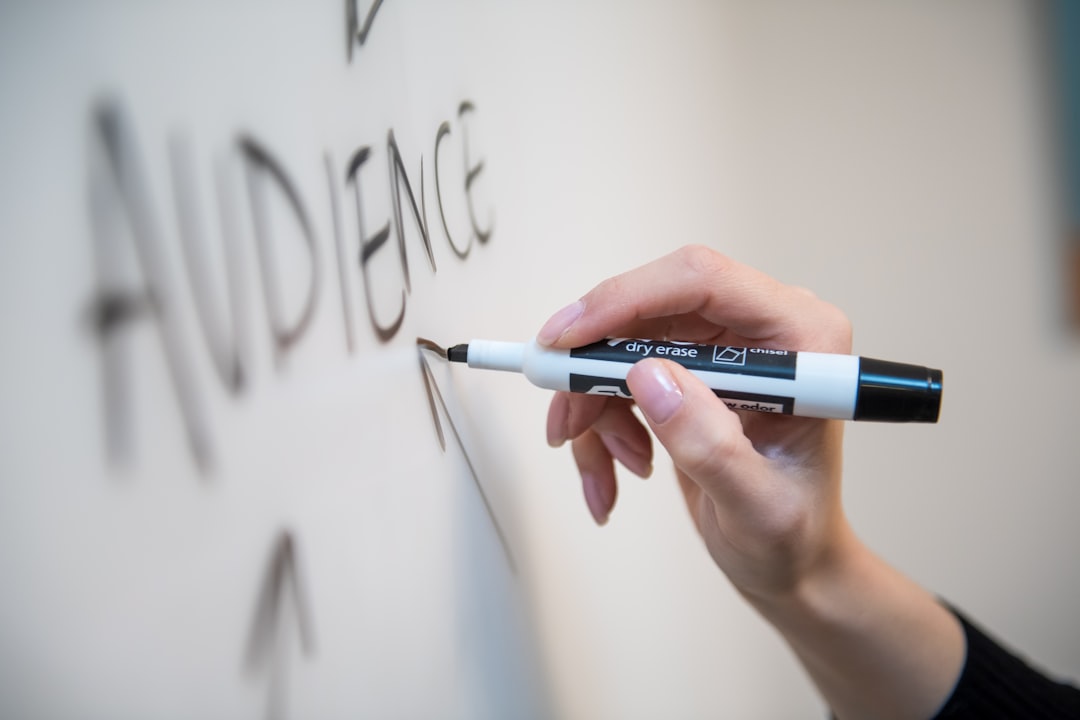 about-01 Womans hand writing the word audience on a whiteboard, with arrows.